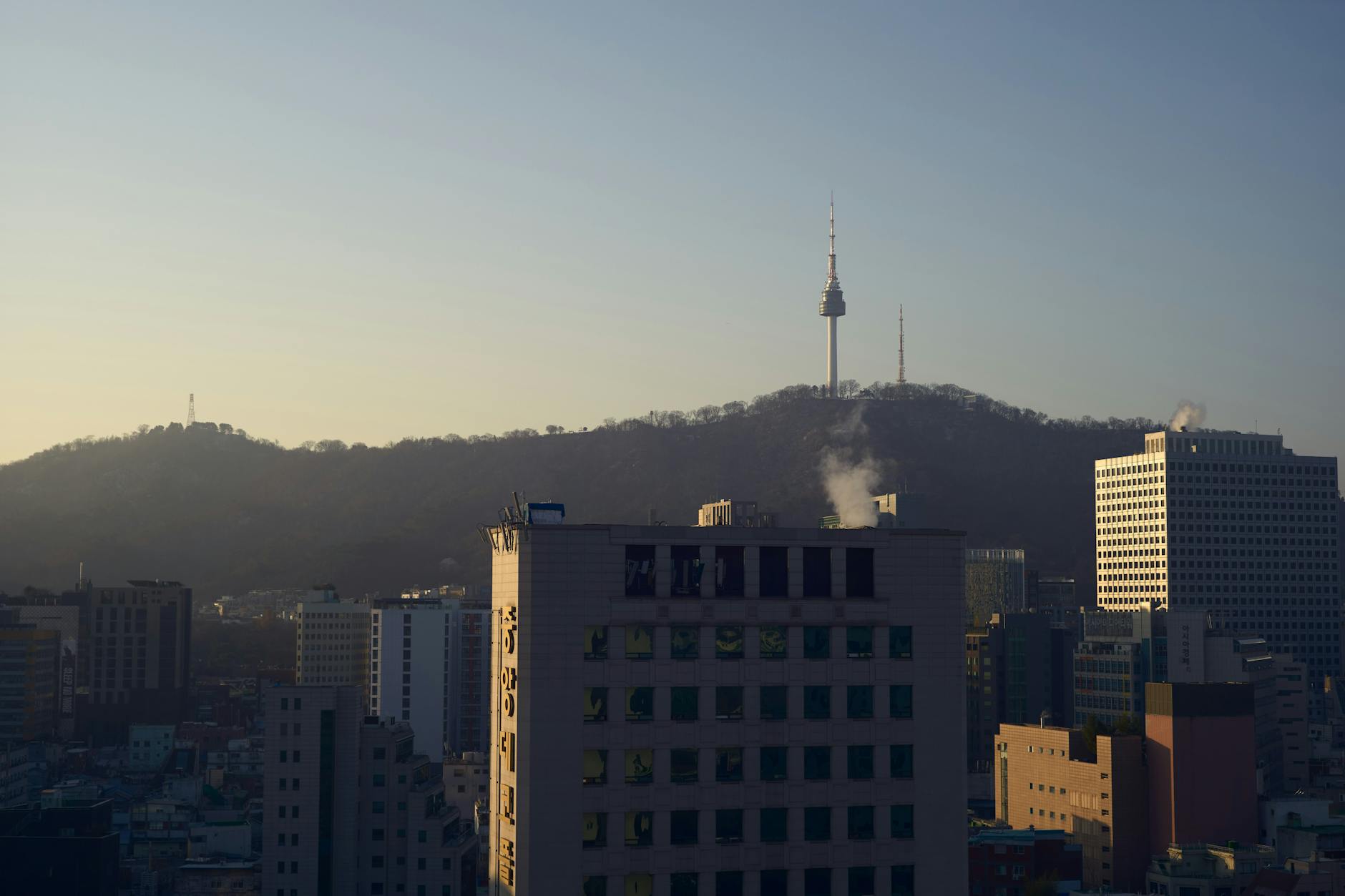 Skyline view of Seoul with Namsan Tower at sunset, highlighting urban landscape and iconic landmark.