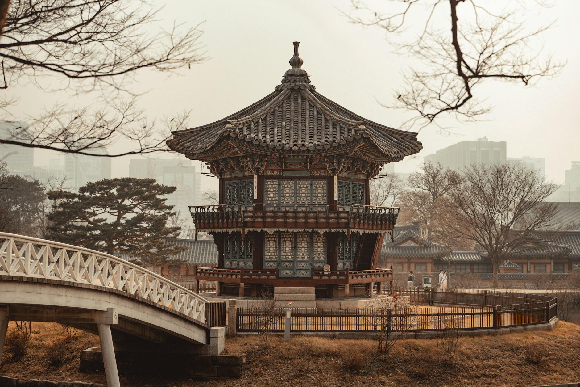 Ancient pagoda with city skyline in background, Gyeongbokgung Palace.