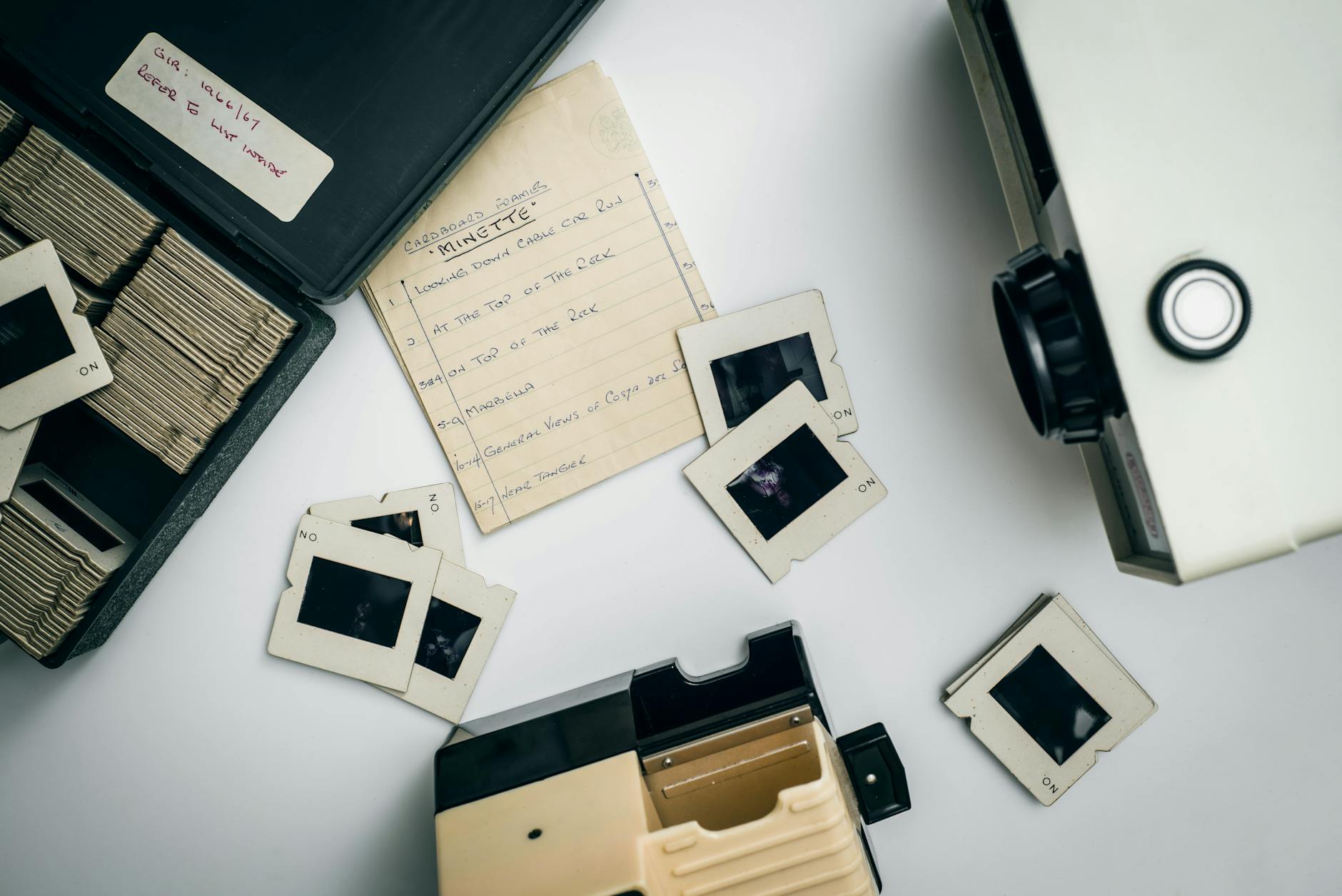 Flat lay of vintage slide projector and film slides, capturing nostalgia in photography.