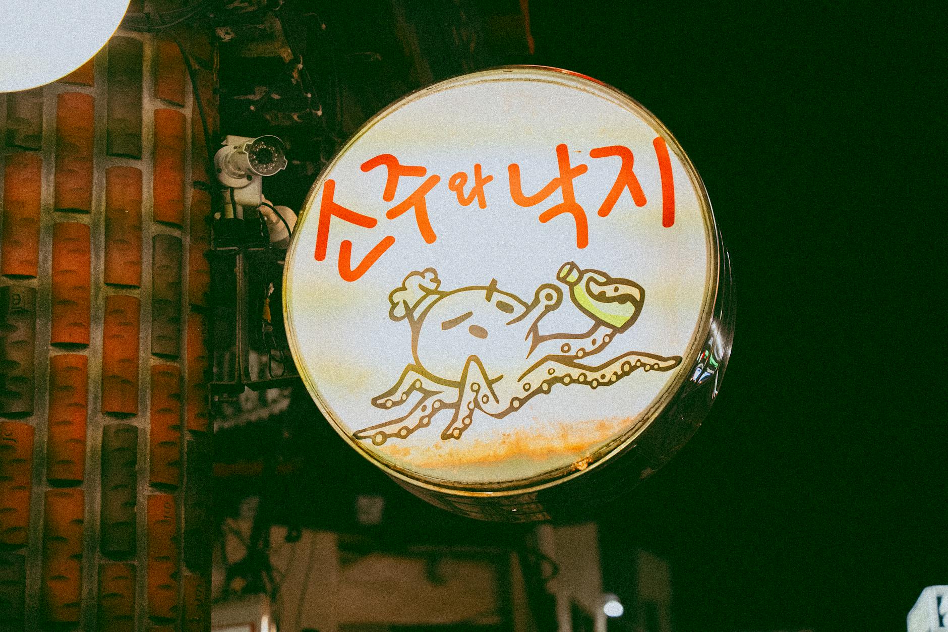 A vibrant signage of a Korean restaurant featuring an octopus illustration against a dark backdrop.