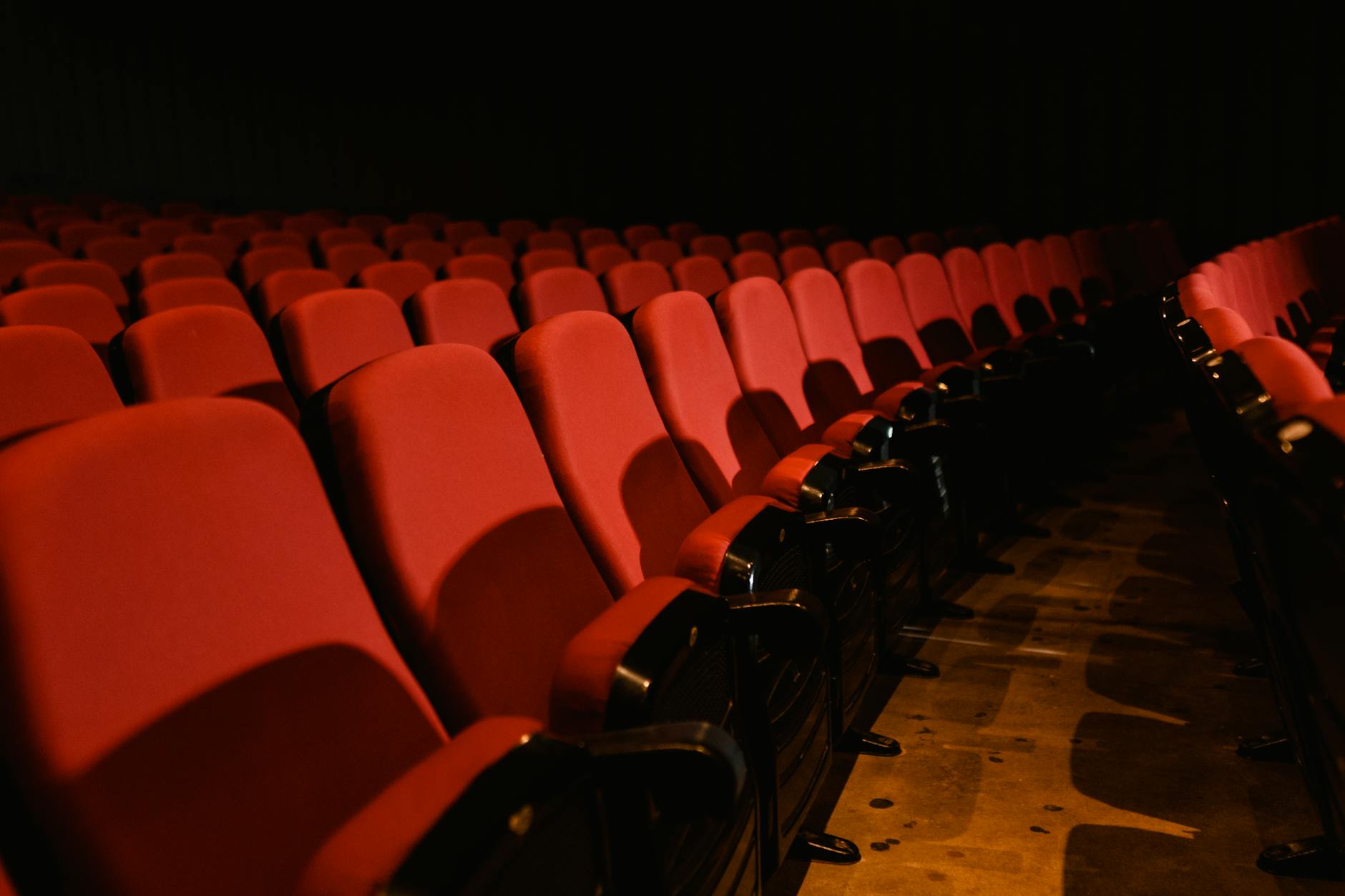 Rows of empty red seats in a dimly lit theater, perfect for cinema themes