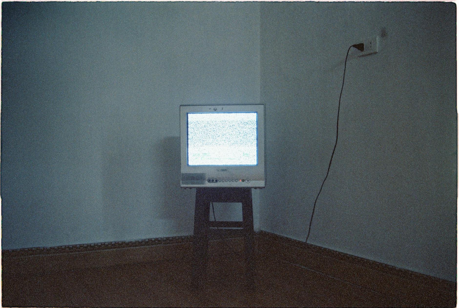 A vintage CRT television displaying static noise in a minimalist room setting.